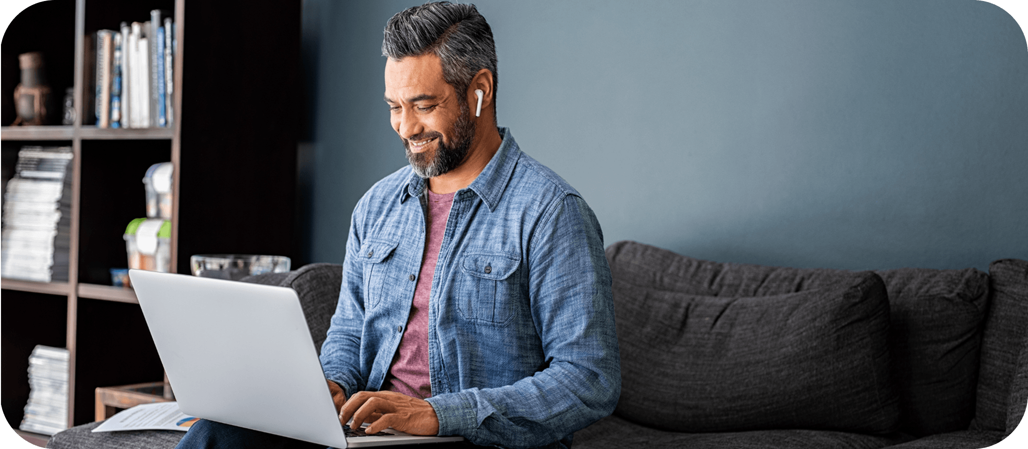 Man on a couch looking something up on a laptop